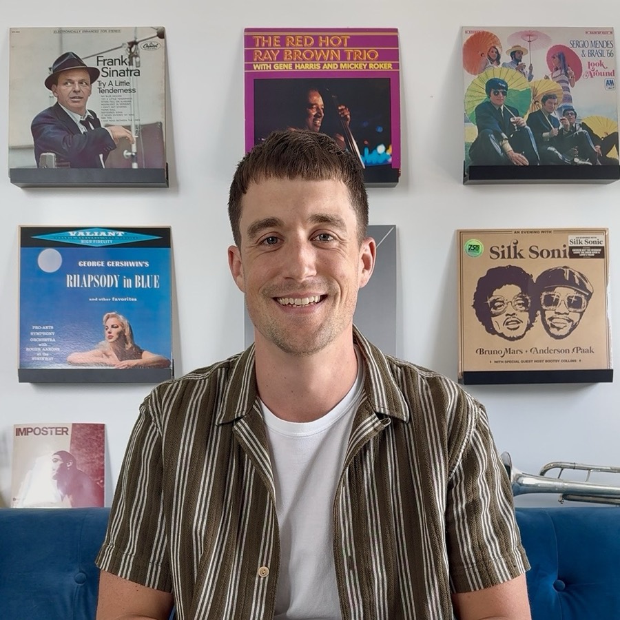 Greg smiling in front of his record wall, with Sinatra, Ray Brown Trio, and Silk Sonic album covers behind him.